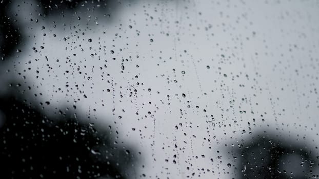 Raindrops texture on the glass window frame of cafe room and nature background in rainy season