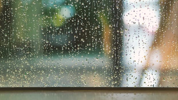 Raindrops texture on the glass window frame of cafe room and nature background in rainy season