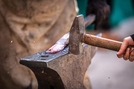 Blacksmith working on metal on anvil at forge detail shot