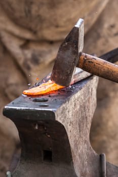 Blacksmith working on metal on anvil at forge detail shot