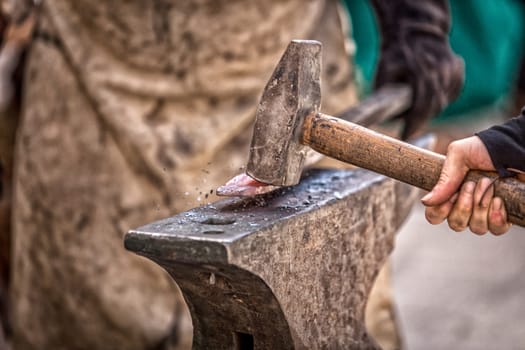 Blacksmith working on metal on anvil at forge detail shot