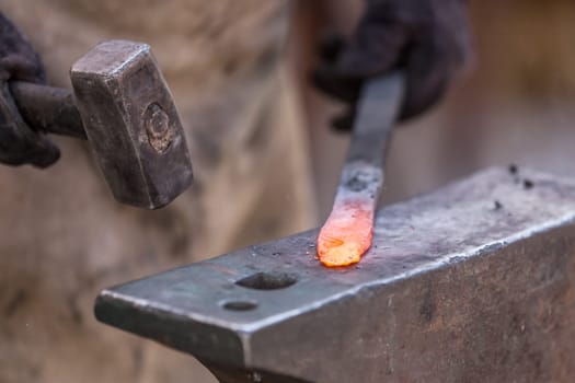 Blacksmith working on metal on anvil at forge detail shot