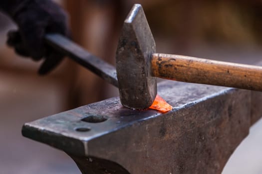 Blacksmith working on metal on anvil at forge detail shot