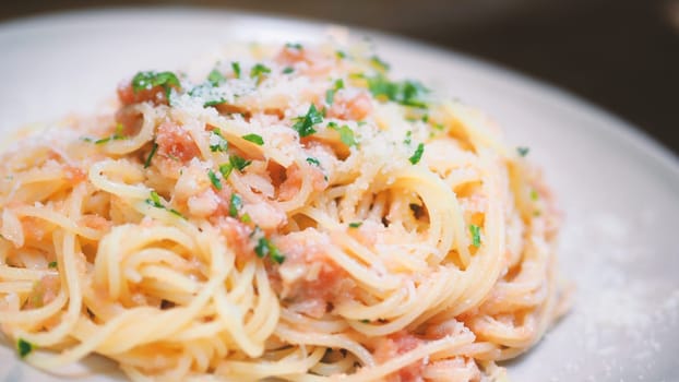 Close-up image of spaghetti sauce tarako which made from fresh cod fish in Japan and mixed with Thai coriander on the top of white plate and very famous italian-japanese menu dish in Thailand restaurant.