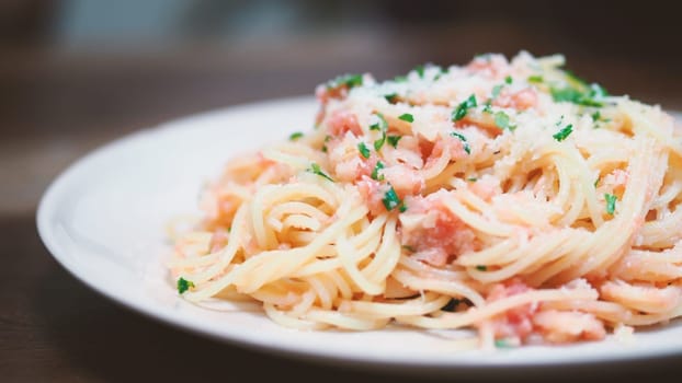 Close-up image of spaghetti sauce tarako which made from fresh cod fish in Japan and mixed with Thai coriander on the top of white plate and very famous italian-japanese menu dish in Thailand restaurant.