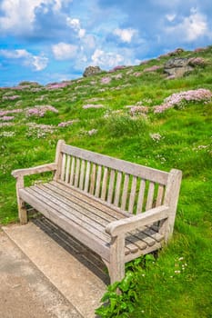 Empty wooden bench for tired walkers on the coastal path along the Cornish coast in St. Ives, Cornwall, England, UK