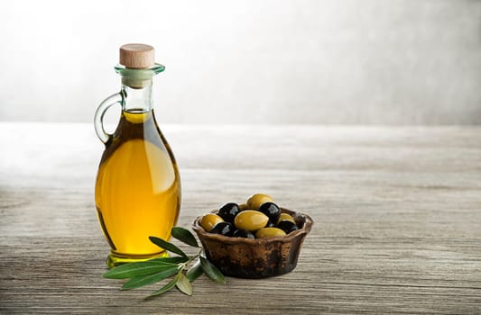Olive oil and olive branch on wooden table