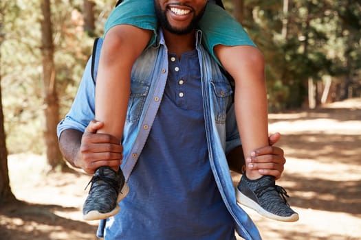 Close Up Of Father Walking In Woods Carrying Son On Shoulders