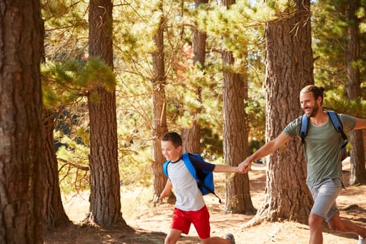 Father And Son On Hiking Adventure Running Through Forest
