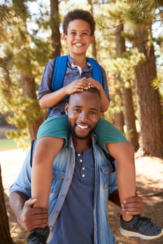 Portrait Of Father Walking In Woods Carrying Son On Shoulders