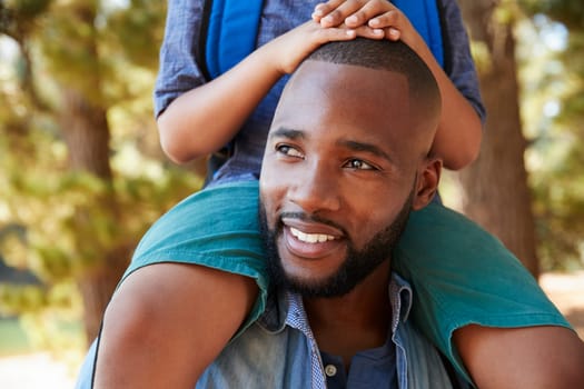 Close Up Of Father Walking In Woods Carrying Son On Shoulders
