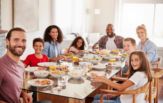 Portrait Of Two Families As They Enjoy Meal At Home Together