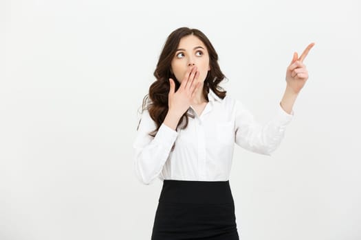 Business Concept: Portrait of surprised young businesswoman pointing finger away to copy space. Isolated on a white background