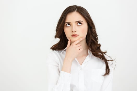 Thinking Caucasian business woman with hand on her chin and looking up on grey backgroud