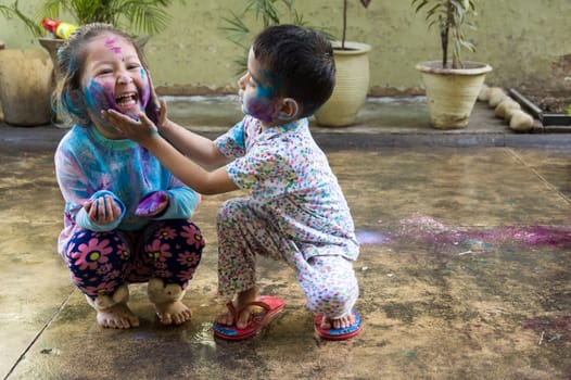 Two Indian kids with their face smeared with colors celebrate Holi, the festival of colors.