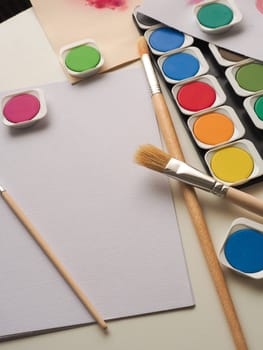 Set of watercolor paint, art brushes and paper on a desk
