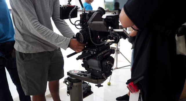 Video camera ultra high definition on pan and tilt head professional tripod with rig and gimbal operated by film crew team that recording or shooting tvc movie at location with monitor.