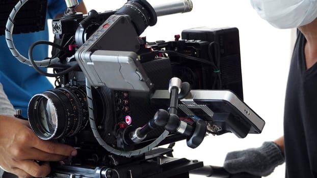 Video camera ultra high definition on pan and tilt head professional tripod with rig and gimbal operated by film crew team that recording or shooting tvc movie at location with monitor.