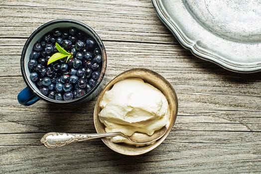 Fresh blueberries with sweet cream served on wooden background
