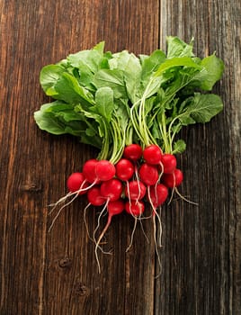 Fresh red radishes on wooden background close up