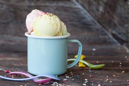 Colorful ice cream balls in enamel cup with sugar sprinkles