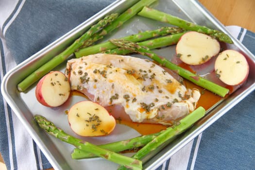 Chicken breast on half sheet pan with asparagus and small red potatoes.