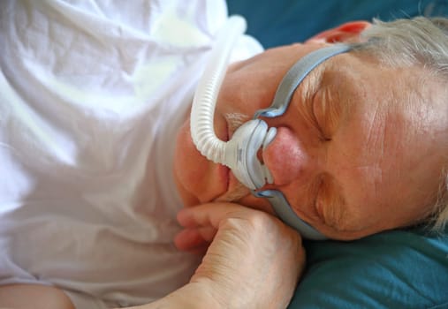 Senior man naps with CPAP machine.