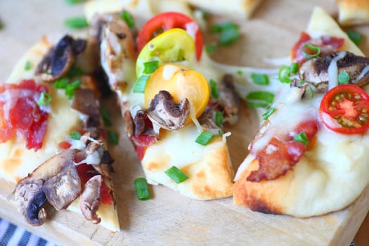 Naan pizza with bacon, mushrooms, cherry tomatoes and scallions