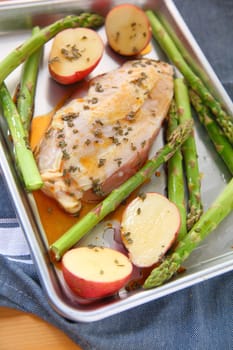 Preparing dinner for one person with chicken breast, potatoes and asparagus
