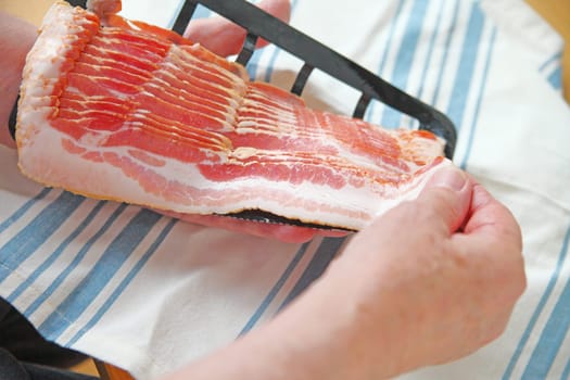 Older man pulls slice of raw bacon from package