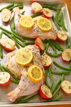 Overhead view of chicken sheet pan meal with potatoes, lemon and green beans.