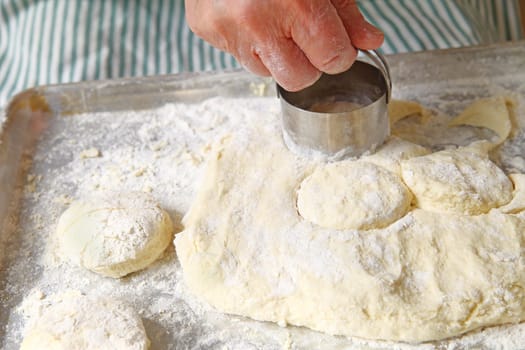 A male cook cuts out biscuits on a floured pan