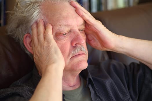 Senior man seated with a bad headache