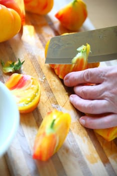 A man cuts up a colorful tomato, vertical view