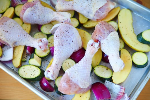 Overhead of chicken legs and vegetables before baking