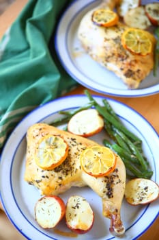 Chicken quarters with green beans and potatoes on blue and white plates from overhead