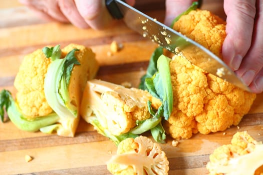 A man preparing a colorful vegetable on a cutting board