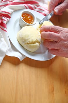 Using a dinner knife to break open biscuits with jam alongside