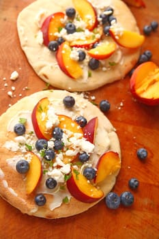 Pizzas made with mascarpone, fresh peaches, blueberries and feta cheese