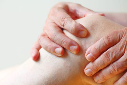 Older man has both hands on a painful knee joint with room for text