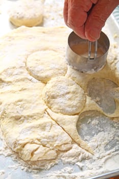 A man uses a metal cutter to make individual biscuits