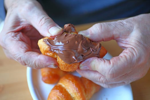 Closeup of man holding a mini-croissant spread with chocolate