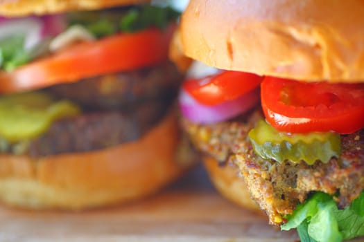 Two sandwiches with meatloaf, tomatoes, pickle, onions and lettuce on brioche buns