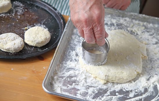 A male cook cuts out biscuits on a floured pan