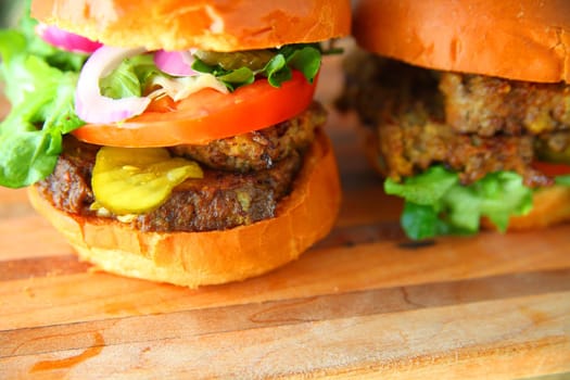 Two meatloaf sandwiches with tomato, lettuce, pickle and onion with copy space.