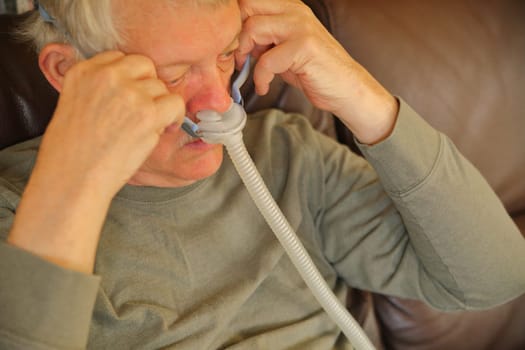 Older man puts on an apparatus for sleep apnea.