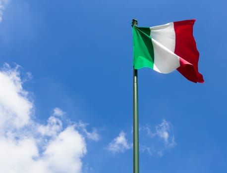 Italy flag waving against blue sky with white clouds. Space for text.