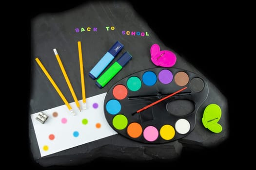 Closeup of colorful school supplies with copy space on blackboard background. Back to school written with colorful letters on blackboard. Concept education..
