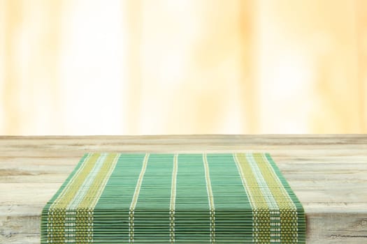 Empty table with green tablecloth over bright background. For your food and product display montage
