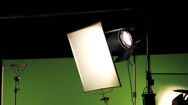 Big studio lighting kit 5000 watt with soft box on tripod and professional green screen background chroma key post production technique shooting or filming for movie or video commercial set up.
